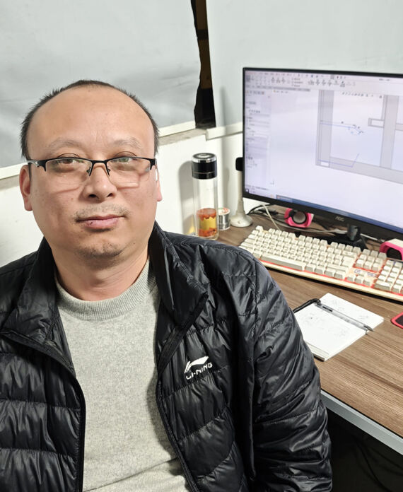 Zhang Daohong (Technical Director) at work desk with technical interface on computer